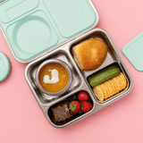 Hot n Cold stainless steel hero lunch box box in mint includes an insulated food jar that sits inside with 2 other compartments containing a sandwich, fruit, and other snacks on a pink background