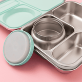 Stainless steel lunch box with mint seals and clasps  with compartments and a thermos on a pink background