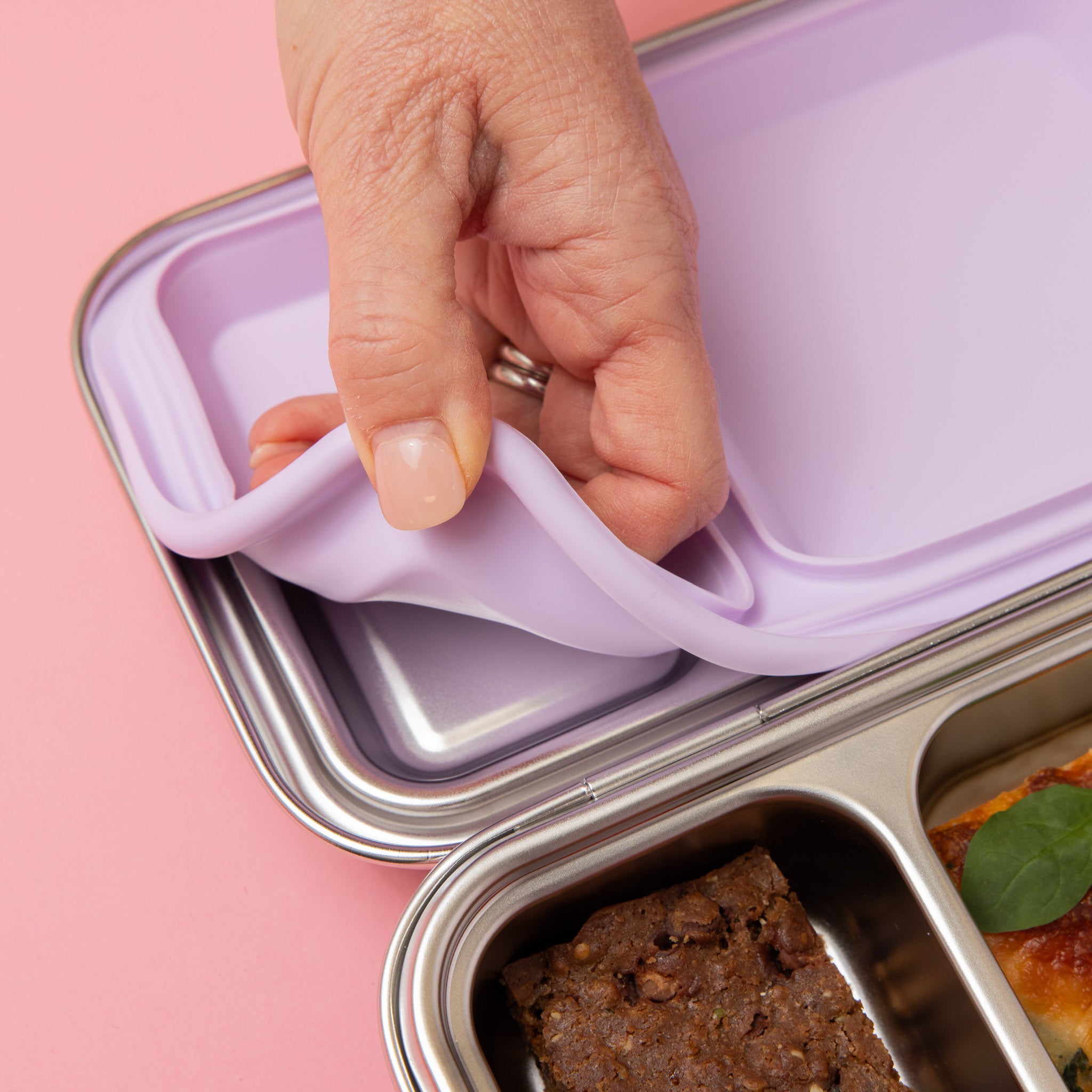 stainless steel two compartment lunch box with soft lilac/purple seals and clasp seal being taken out