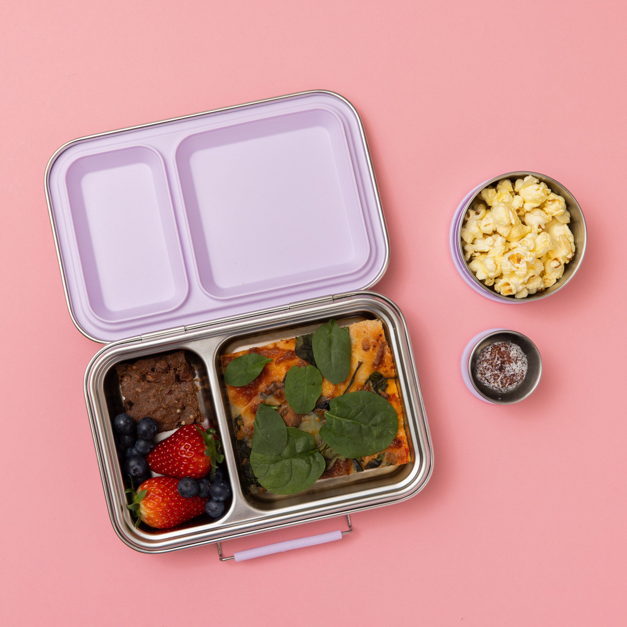 stainless steel two compartment lunch box with soft lilac/purple seals and clasp full of food