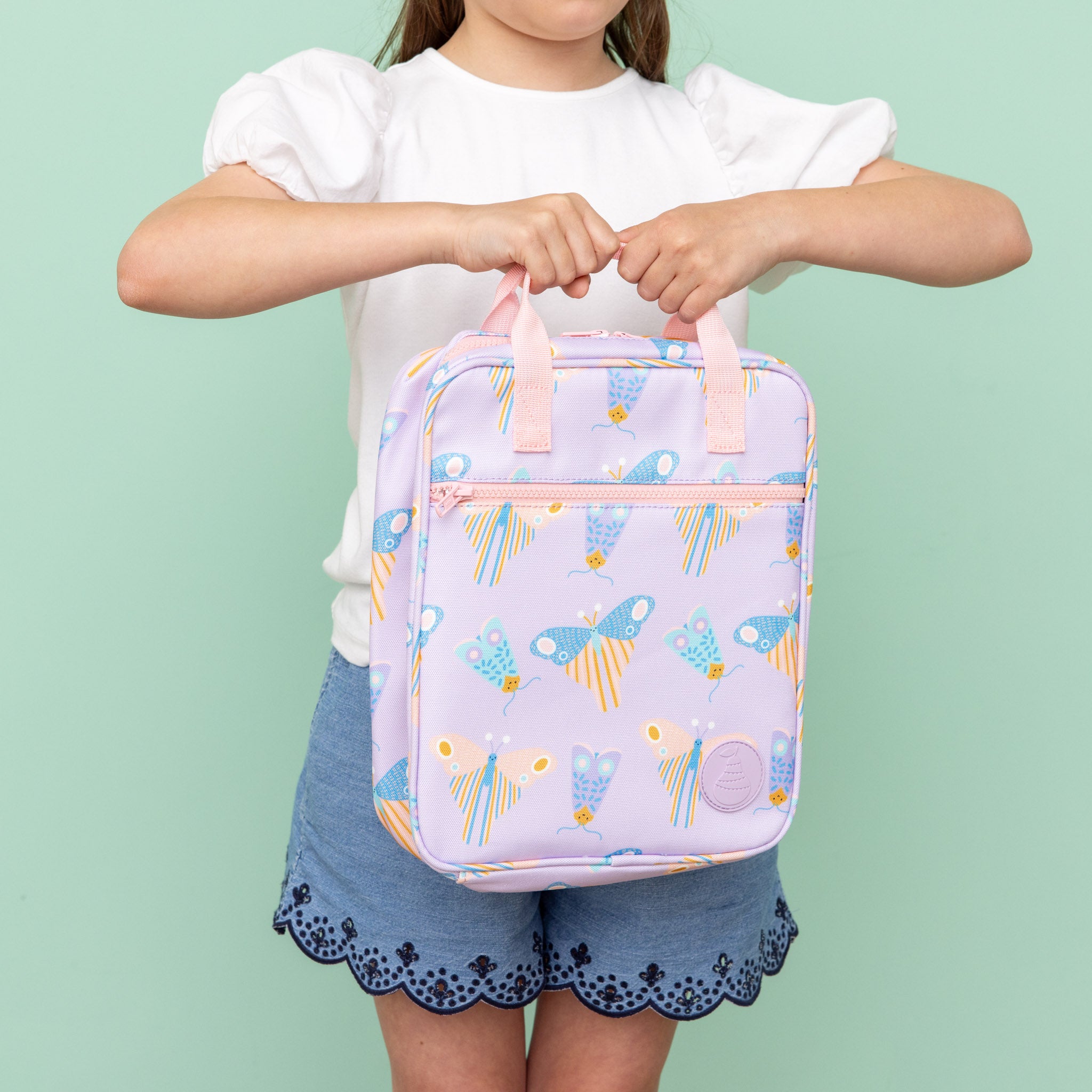jumbo sized lunch bag with scandi butterfly print on light purple background being held by a child