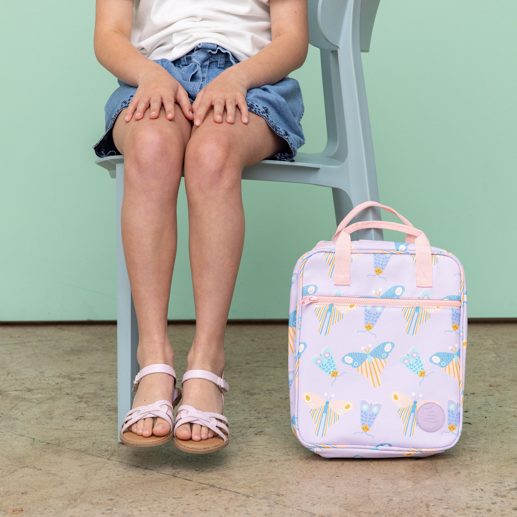 jumbo sized lunch bag with scandi butterfly print on light purple background showing it sitting at a child's feet