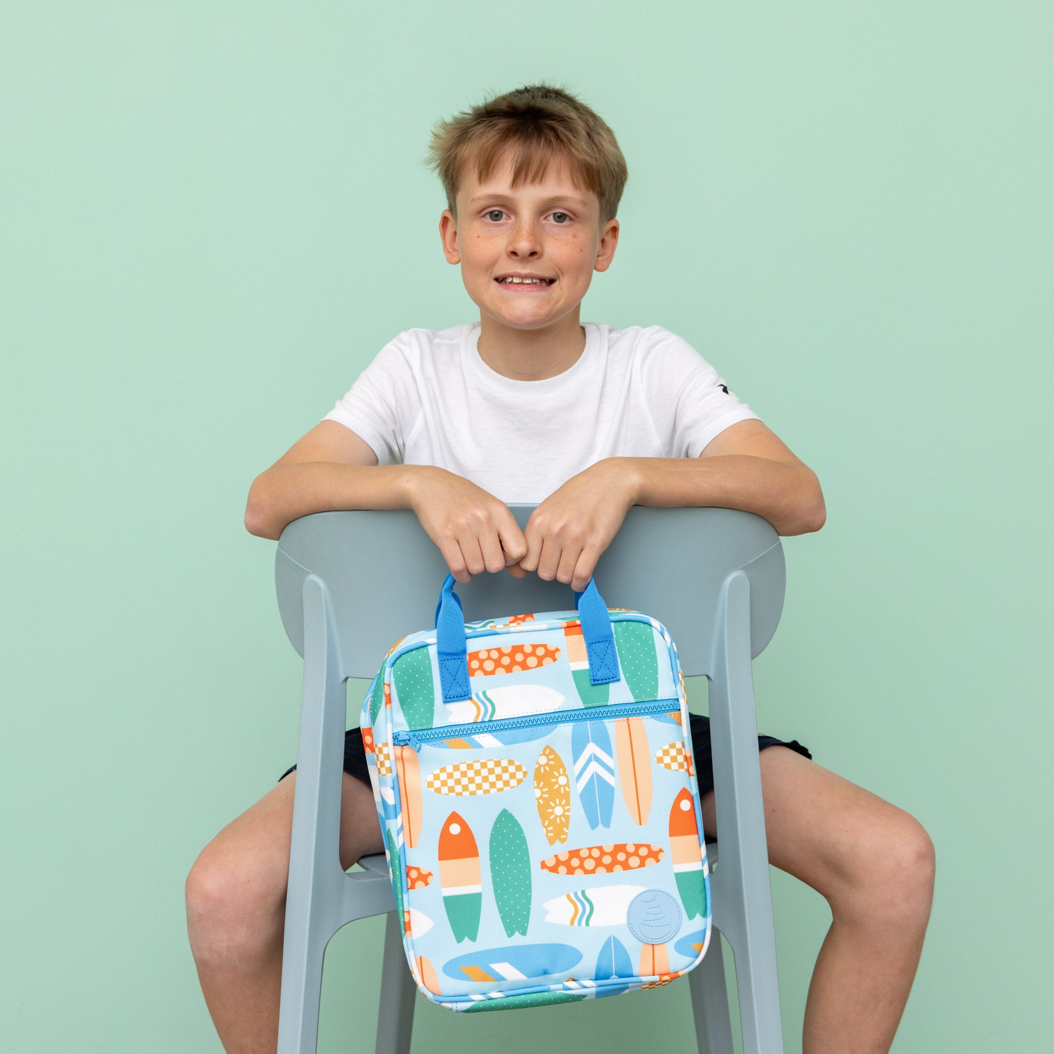 jumbo sized lunch bag with vintage surfboard print being held by child sitting on chair