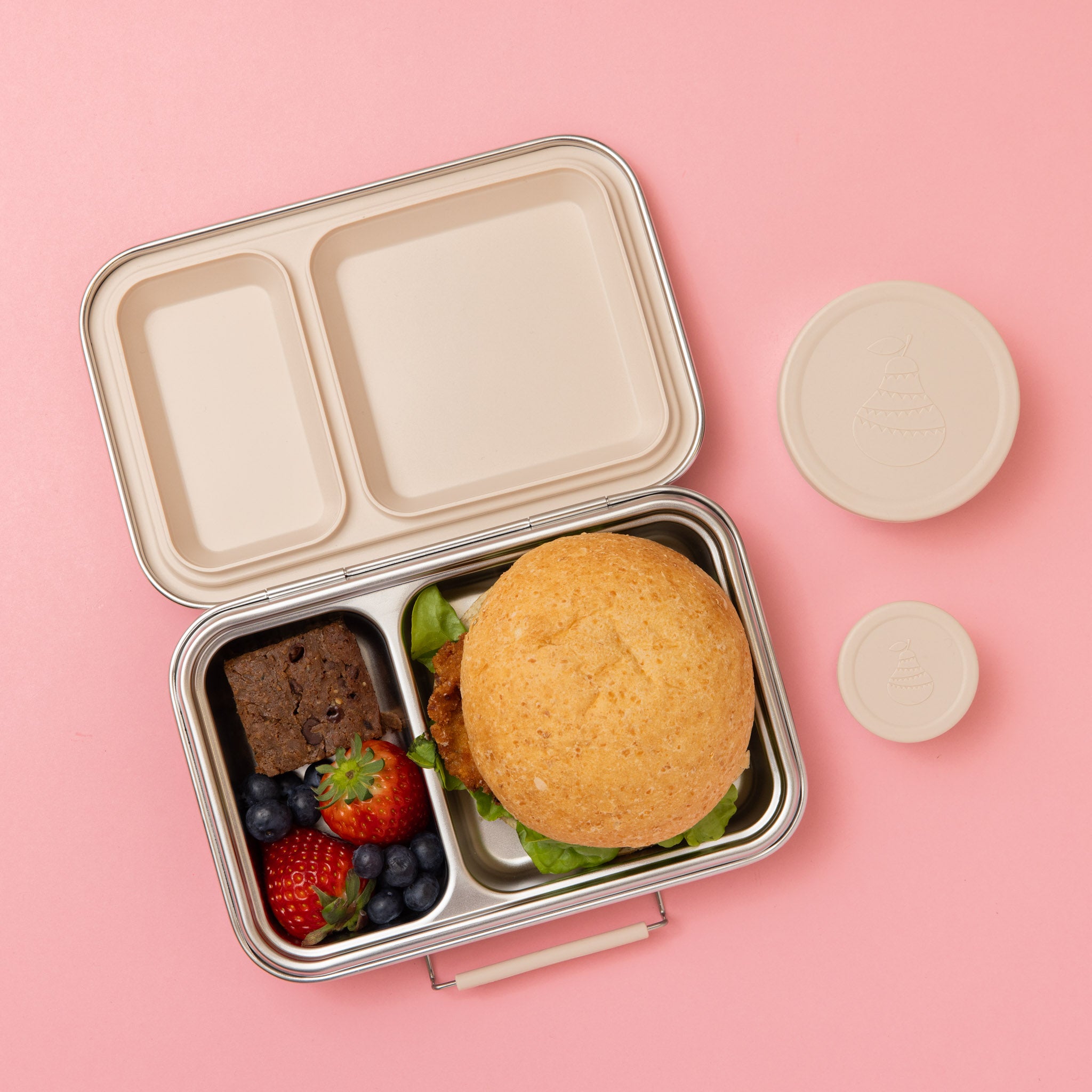 two compartment stainless steel lunch box with oatmeal seals and silicone clasp full of food