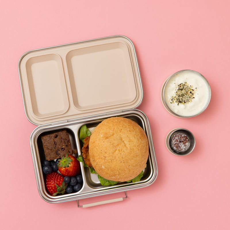 two compartment stainless steel lunch box with oatmeal seals and silicone clasp full of food