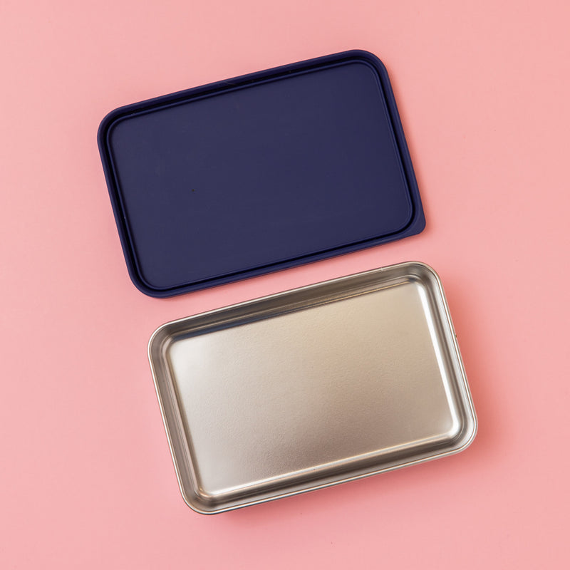 large stainless steel salad container or lunch box with navy silicone lid on pink background empty 