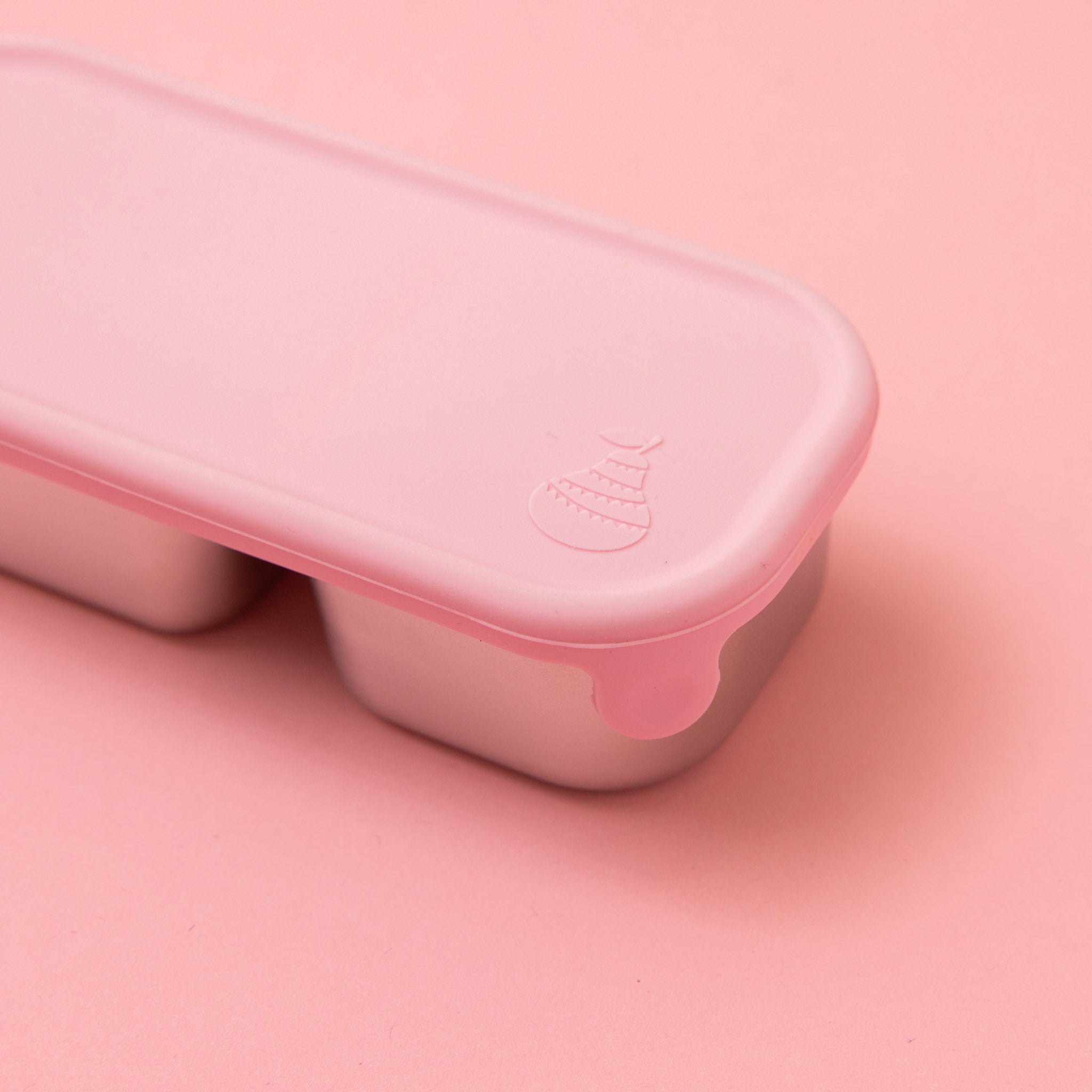 two compartment stainless steel snack container with light pink silicone lid shown from side with pear logo and tab 
