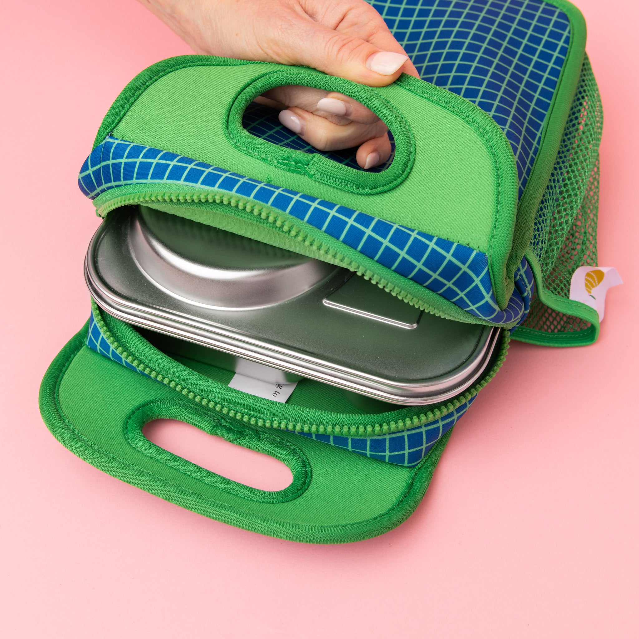 navy neoprene lunch bag with green gridlines and green interior holding out hero lunch box 