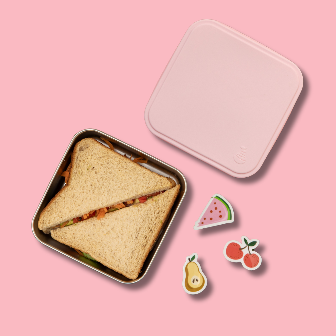 stainless steel square container or sandwich box with pink lid on a pink background with full sized sandwich  